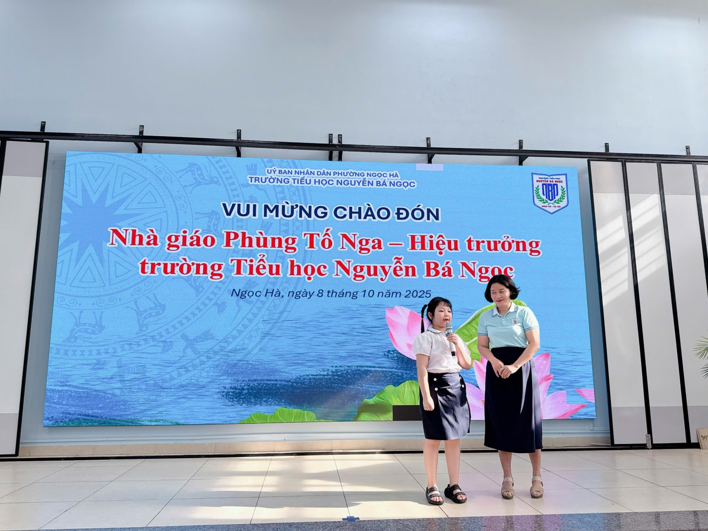 Two women standing in front of a large sign
Description automatically generated